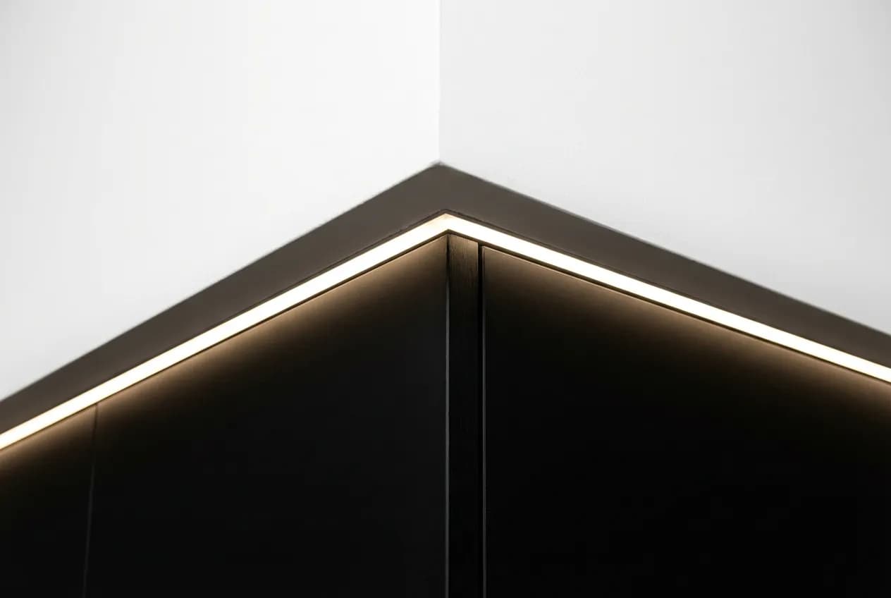 Cartongesso Sopra Pensili Cucina: Guida, Idee e Costi 2024 Gros plan sur la jonction parfaite entre un cartongesso blanc et un pensile de cuisine noir, soulignée par une ligne de lumière LED.