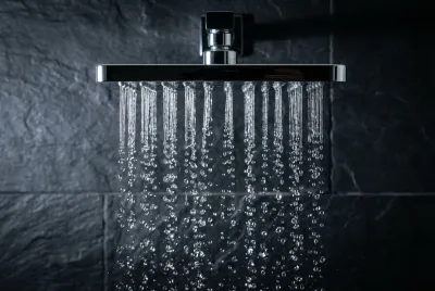 Gros plan sur un pommeau de douche effet pluie moderne, mettant en évidence la clarté et le mouvement de l'eau.