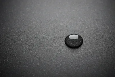 Gros plan sur la texture d'un évier en Granitek gris anthracite avec une goutte d'eau perlant à la surface, illustrant ses propriétés hydrofuges.
