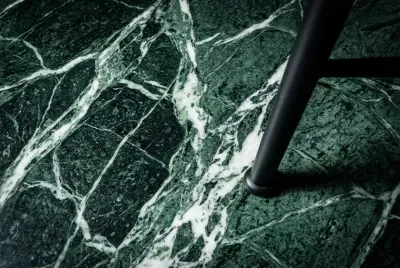 Gros plan iconique sur la texture et les veines d'un sol en marbre poli des années 70, créant un contraste avec un pied de chaise moderne.