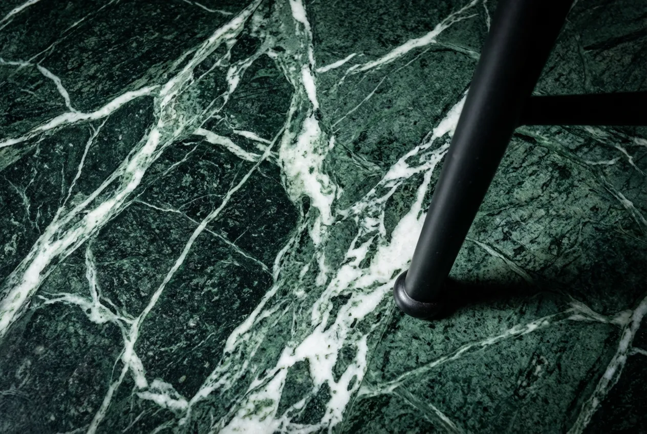 Gros plan iconique sur la texture et les veines d'un sol en marbre poli des années 70, créant un contraste avec un pied de chaise moderne.