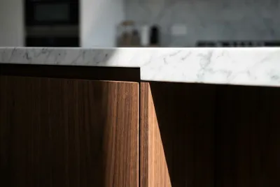 Gros plan sur la jonction parfaite entre un plan de travail en marbre et un meuble de cuisine Arrex en bois, mettant en avant la qualité des finitions.