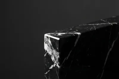 Gros plan iconique sur l'angle d'une marche d'escalier en marbre noir Marquina, mettant en évidence le contraste saisissant de ses veines blanches et sa finition parfaite.