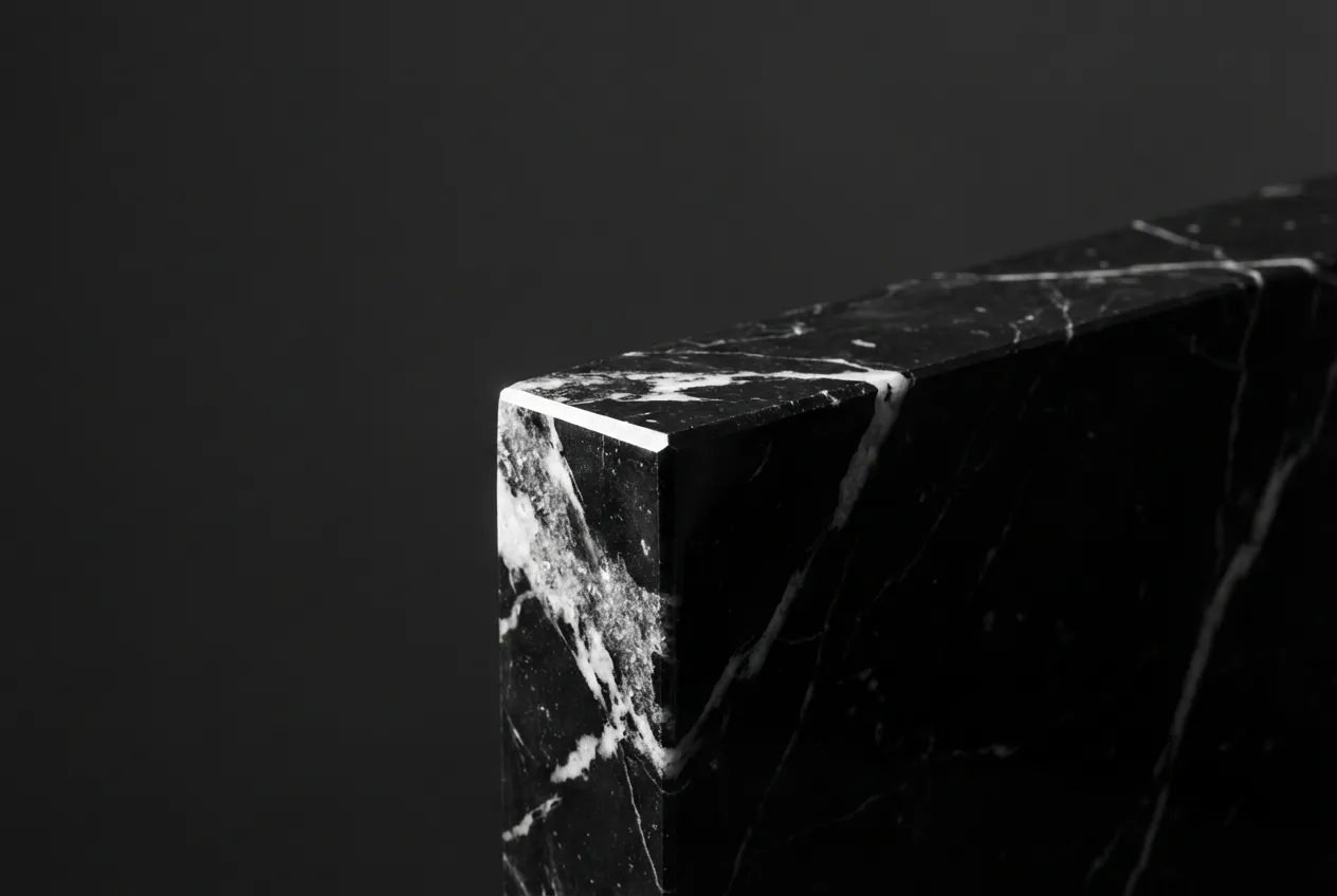 Gros plan iconique sur l'angle d'une marche d'escalier en marbre noir Marquina, mettant en évidence le contraste saisissant de ses veines blanches et sa finition parfaite.