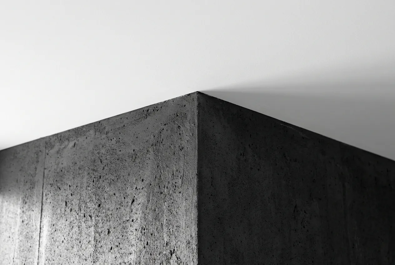 Gros plan géométrique et minimaliste de l'angle parfait entre un mur gris foncé et un plafond blanc.